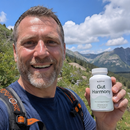 A 3x3 collage of women and men holding white supplement bottles labeled 'Gut Harmony' in various real-world settings, including beach scenes, home interiors, and outdoor locations.