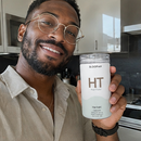 A 3x3 collage of nine photos showing different people holding and drinking from a clear plastic travel can with a white lid. The can has a clear cap, a white body, and a printed label with the brand name 'HT' and 'BIOFLAVONICS' at the top.